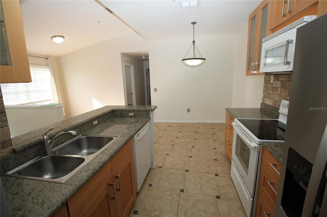 kitchen with pendant lighting, dark stone countertops, white appliances, and sink