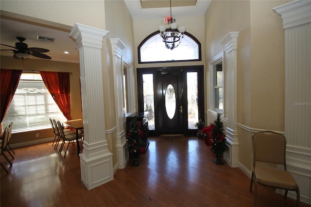 foyer with a towering ceiling, ceiling fan with notable chandelier, dark hardwood / wood-style floors, and plenty of natural light