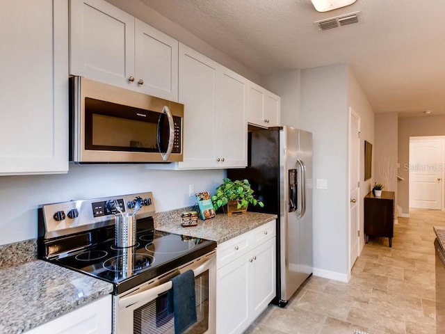 kitchen featuring light stone countertops, white cabinetry, a textured ceiling, and appliances with stainless steel finishes