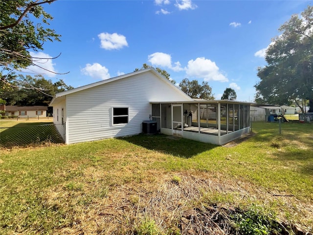 back of property with a sunroom, a yard, and central AC