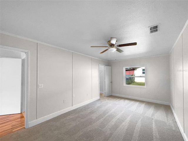 carpeted spare room with a textured ceiling, ceiling fan, and crown molding