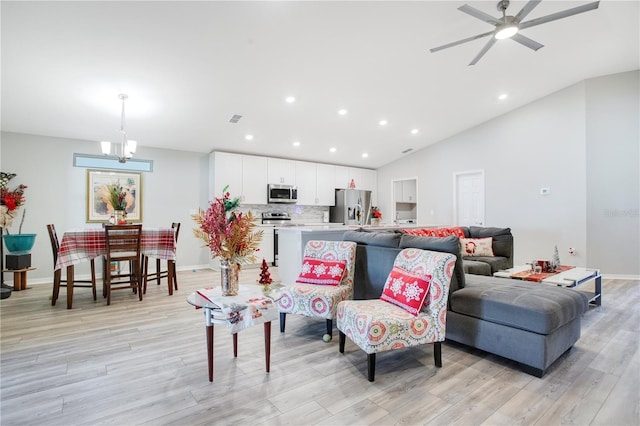 living room featuring ceiling fan with notable chandelier, light hardwood / wood-style floors, and vaulted ceiling