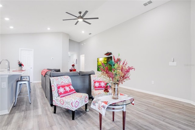 living area with light hardwood / wood-style floors, high vaulted ceiling, ceiling fan, and sink