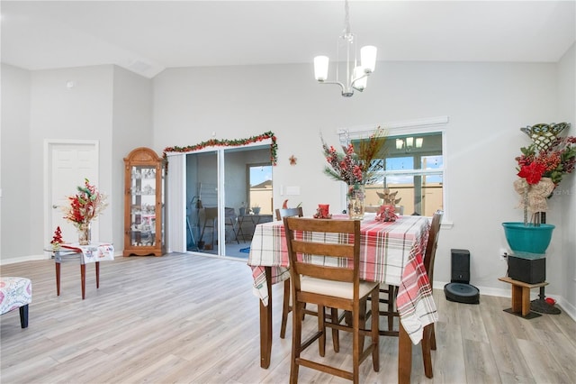 dining area featuring a chandelier, light wood-type flooring, and high vaulted ceiling