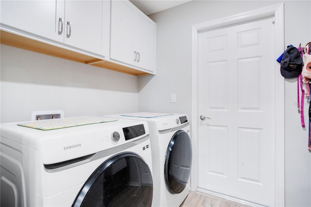 laundry room with cabinets, light wood-type flooring, and washer and clothes dryer