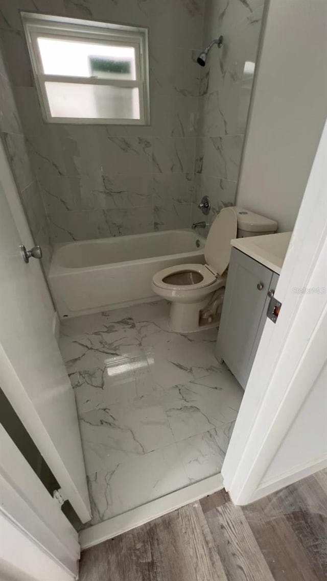 full bathroom featuring hardwood / wood-style flooring, vanity, toilet, and tiled shower / bath combo