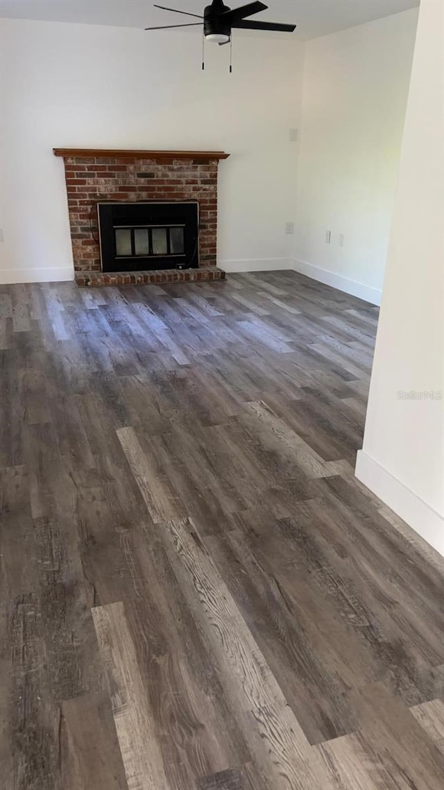 unfurnished living room featuring ceiling fan, a fireplace, and dark hardwood / wood-style floors