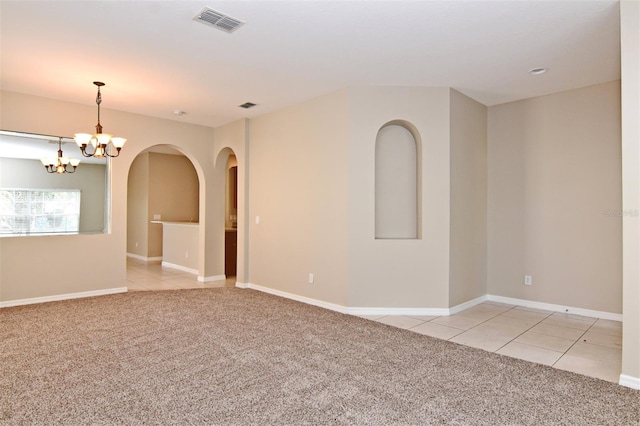 carpeted spare room featuring an inviting chandelier