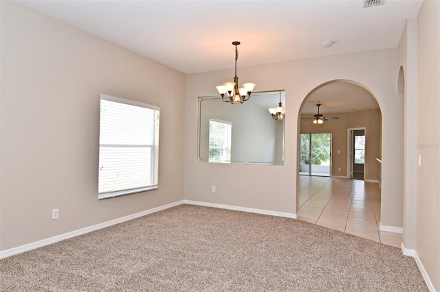 carpeted spare room with ceiling fan with notable chandelier