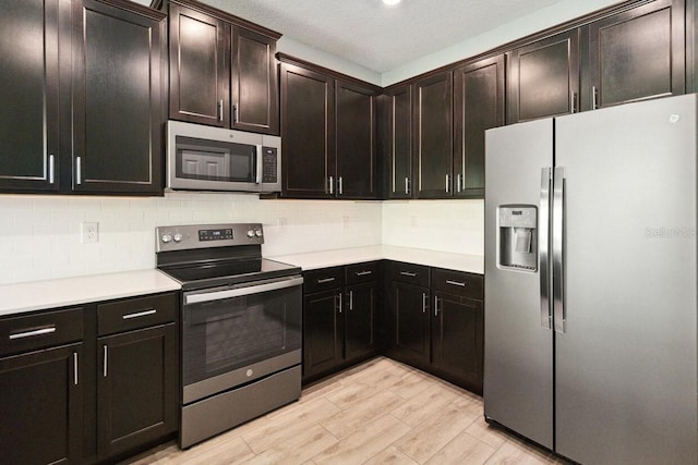 kitchen with dark brown cabinetry, tasteful backsplash, light hardwood / wood-style floors, a textured ceiling, and appliances with stainless steel finishes