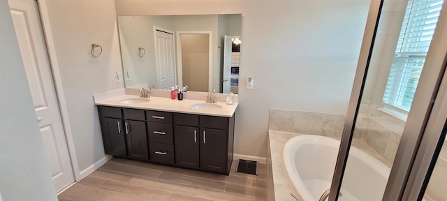 bathroom featuring tiled bath and vanity