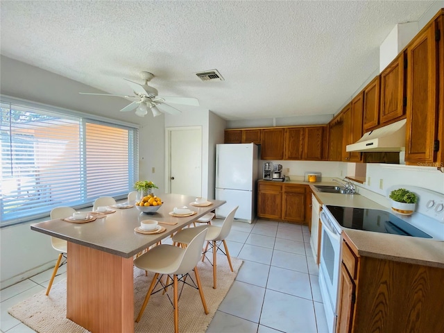 kitchen with ceiling fan, a center island, white appliances, a breakfast bar, and light tile patterned flooring