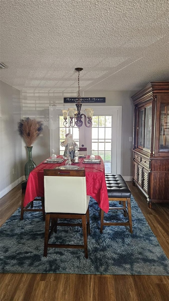 dining space with a chandelier, dark wood-type flooring, and a textured ceiling