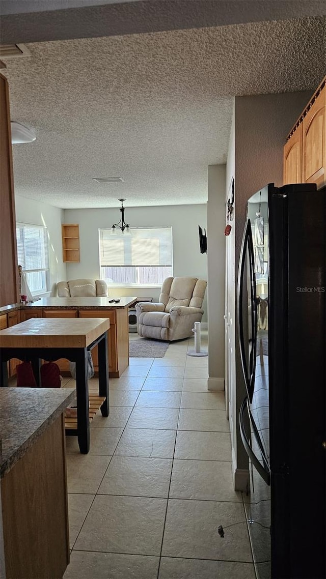 kitchen featuring a textured ceiling, black fridge, and light tile patterned flooring