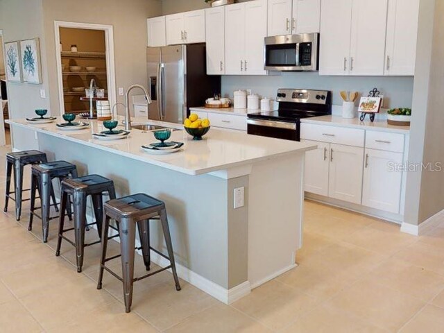 kitchen with white cabinetry, sink, a kitchen breakfast bar, a center island with sink, and appliances with stainless steel finishes