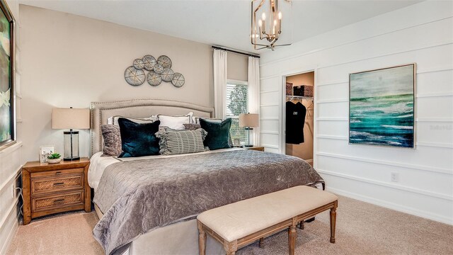 bedroom with a walk in closet, a closet, light colored carpet, and a chandelier