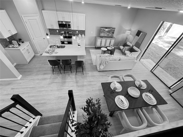 living room with a textured ceiling, light wood-type flooring, and sink