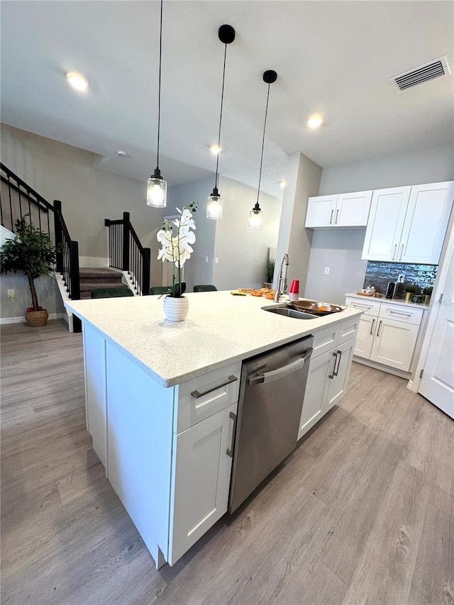 kitchen with white cabinets, dishwasher, and an island with sink