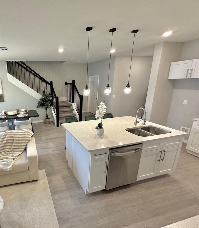 kitchen featuring stainless steel dishwasher, sink, decorative light fixtures, white cabinets, and light hardwood / wood-style floors