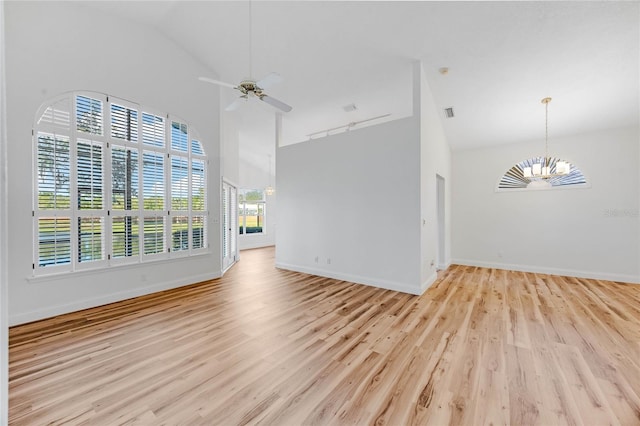 unfurnished living room featuring ceiling fan with notable chandelier, high vaulted ceiling, and light hardwood / wood-style flooring