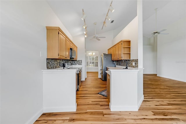 kitchen with light hardwood / wood-style floors, stainless steel appliances, high vaulted ceiling, and tasteful backsplash