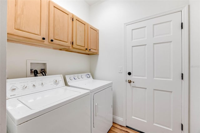 laundry area featuring separate washer and dryer, light hardwood / wood-style flooring, and cabinets