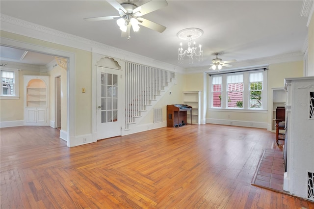 unfurnished living room featuring built in shelves, crown molding, and ceiling fan with notable chandelier