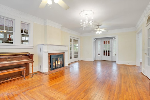 unfurnished living room with ceiling fan with notable chandelier, light hardwood / wood-style flooring, crown molding, and a brick fireplace