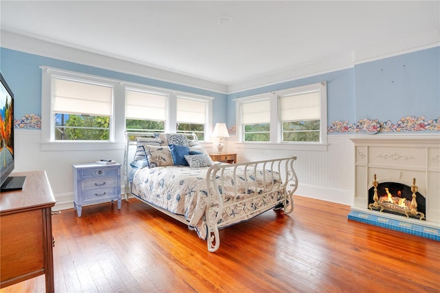 bedroom featuring wood-type flooring, multiple windows, and ornamental molding