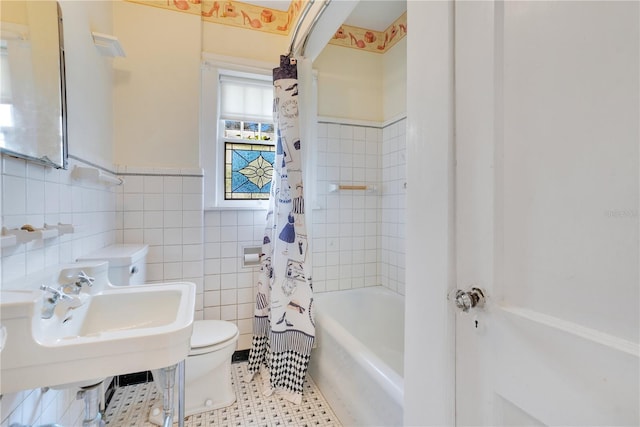 bathroom with tile patterned floors, toilet, shower / bathtub combination with curtain, and tile walls