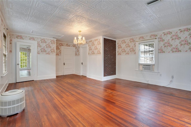 empty room featuring hardwood / wood-style floors, cooling unit, and a chandelier