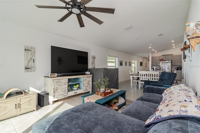 living room with ceiling fan, light tile patterned floors, and vaulted ceiling