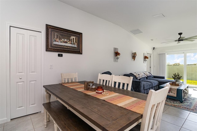 dining space with ceiling fan, light tile patterned floors, and vaulted ceiling