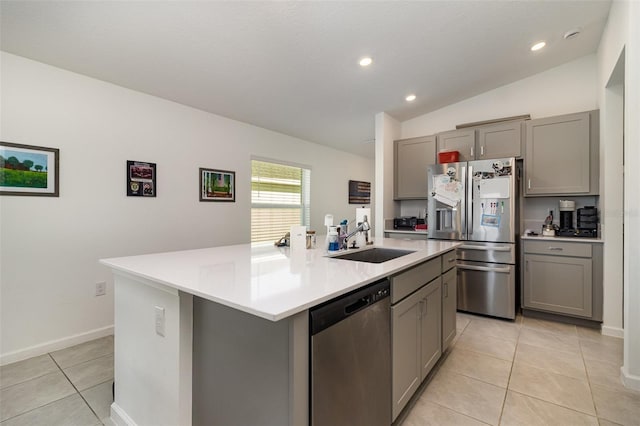 kitchen with gray cabinetry, stainless steel appliances, vaulted ceiling, sink, and an island with sink