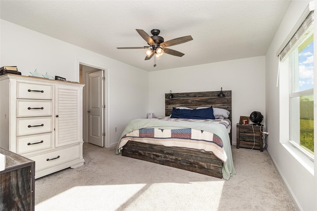 carpeted bedroom featuring ceiling fan and a textured ceiling