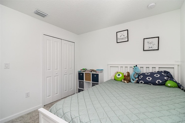 carpeted bedroom with a closet and a textured ceiling