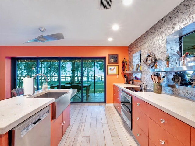 kitchen with sink, stainless steel dishwasher, ceiling fan, light hardwood / wood-style floors, and light stone countertops