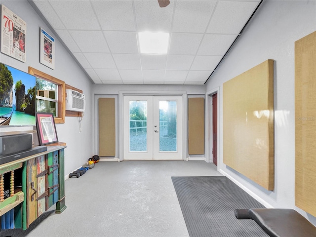 recreation room featuring a drop ceiling, an AC wall unit, a wealth of natural light, and french doors