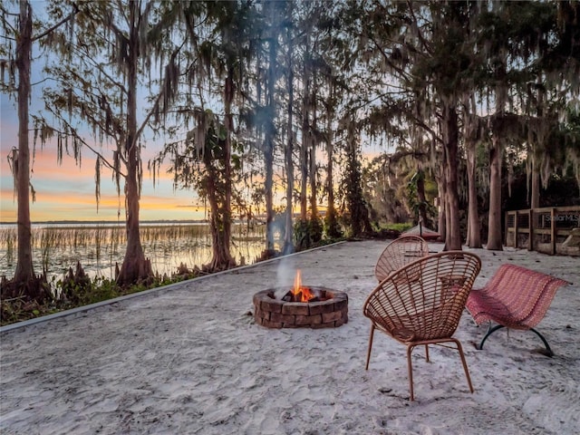 patio terrace at dusk with a water view and a fire pit