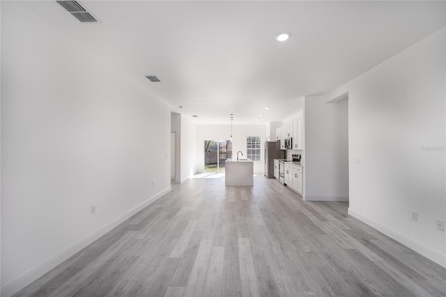 unfurnished living room with light wood-type flooring and sink