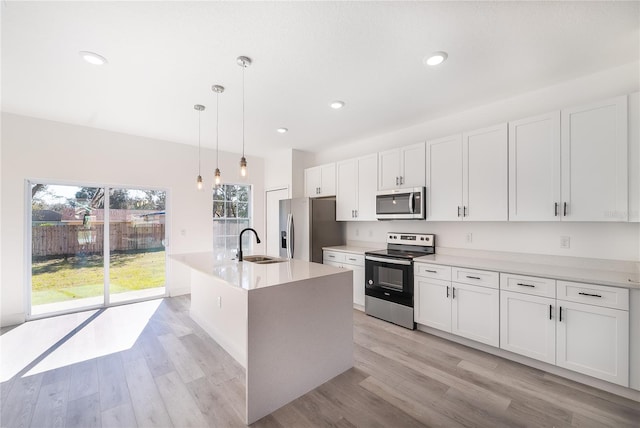 kitchen with white cabinetry, sink, light hardwood / wood-style flooring, pendant lighting, and appliances with stainless steel finishes