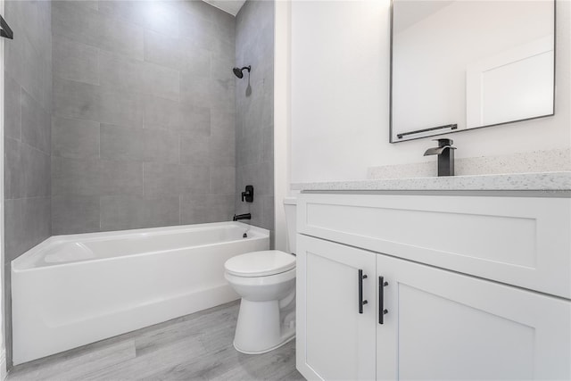 full bathroom featuring hardwood / wood-style floors, vanity, toilet, and tiled shower / bath