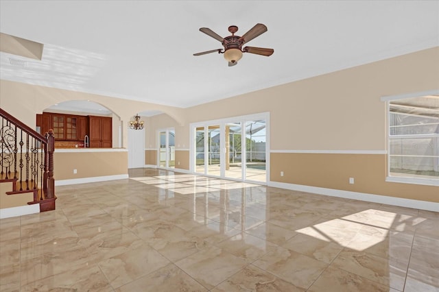 unfurnished living room featuring ceiling fan with notable chandelier