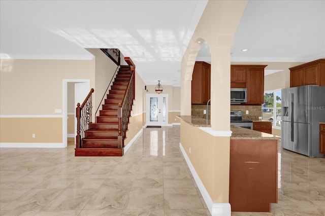 kitchen featuring backsplash, crown molding, light stone countertops, kitchen peninsula, and stainless steel appliances