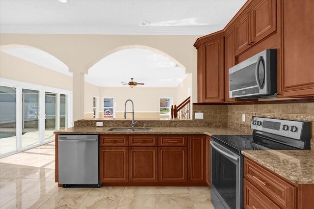 kitchen featuring stone counters, sink, ceiling fan, appliances with stainless steel finishes, and tasteful backsplash