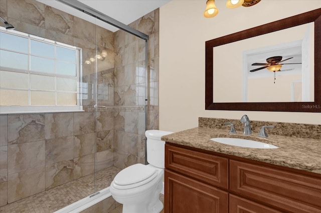 bathroom featuring vanity, a shower with door, toilet, and ceiling fan