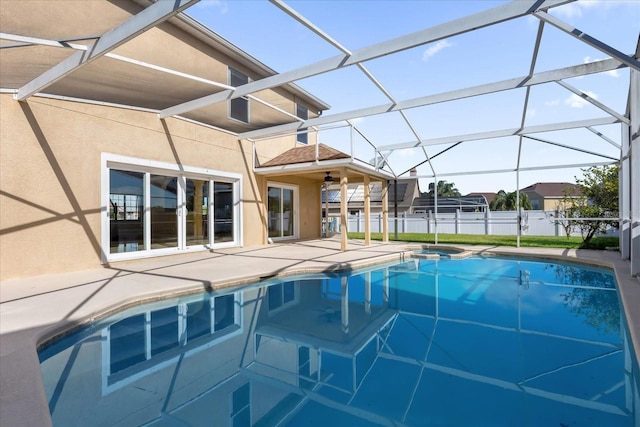 view of pool with glass enclosure, ceiling fan, and a patio