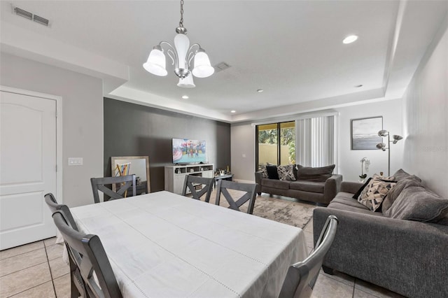 tiled dining space with a notable chandelier and a tray ceiling