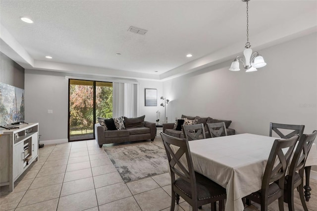 tiled dining space with a textured ceiling and an inviting chandelier