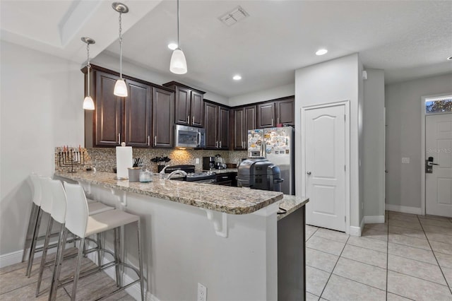 kitchen featuring kitchen peninsula, appliances with stainless steel finishes, backsplash, light stone counters, and hanging light fixtures